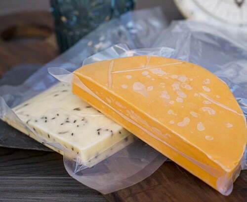 Custom vacuum pouches for cheese Two pieces of cheese vacuum packaged on a wood board